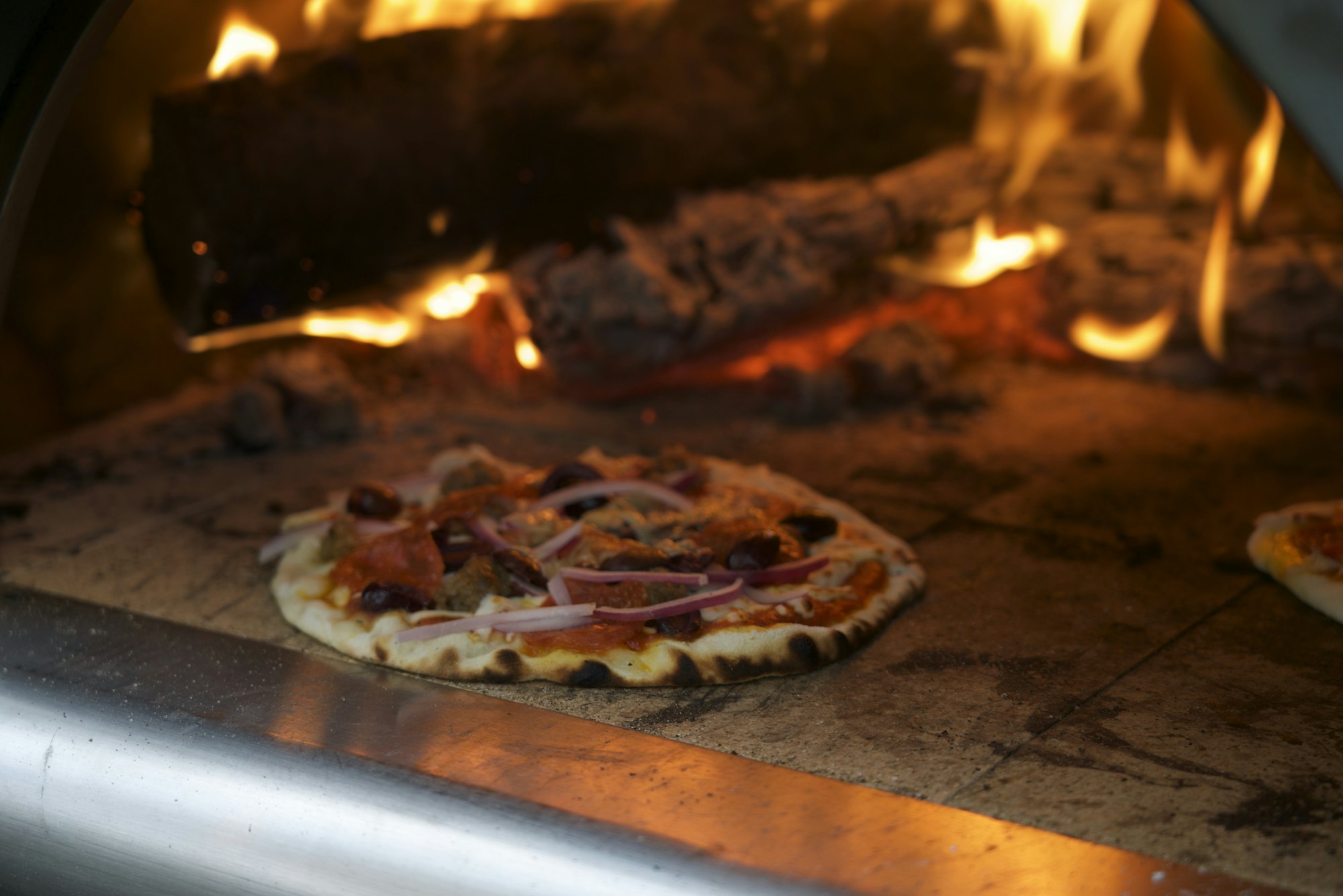 Pizza horneándose dentro de un horno de leña